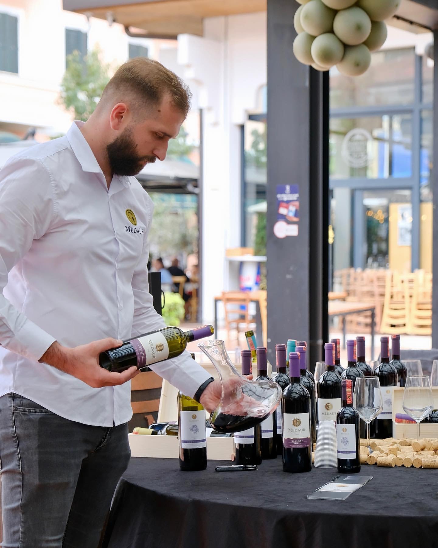 Medaur winery ambassador presenting the wine labels and pouring red wine at a wine festival in albania 